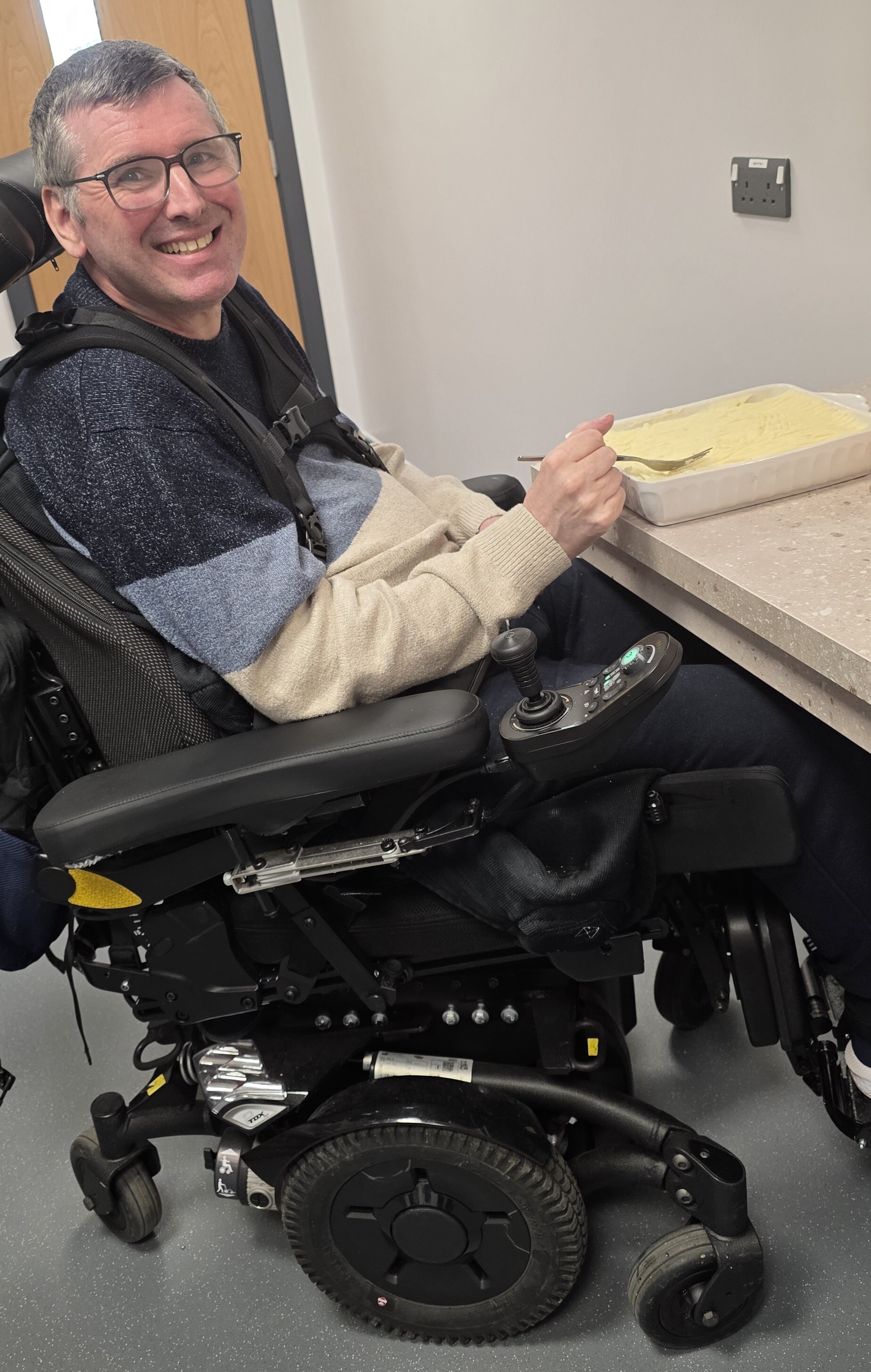 Person smiling at the camera while preparing food.