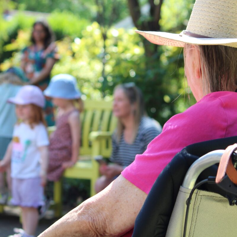 Lady in garden looking at young children