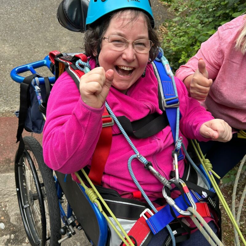 Person in climbing harness and helmet smiling at camera